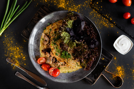Belorussian National food - draniki. Traditional eating concept. Dark background with plate with pancake with meat with vegetables. Top view with special copyspace for text and design.の写真素材