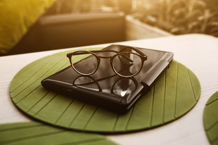 Modern glasses of businesswomann lying on notebook on table in cafe. Freelance working in...