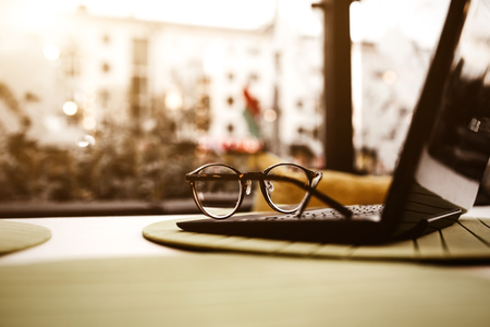Modern glasses of businesswomann lying on notebook on table in cafe. Freelance working in restaurant. Business background. Flare copyspace for text and design.の写真素材