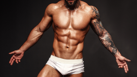 Bodybuilder image with muscle man torso. Banner image of sexy  with muscular body. Portrait of sexy male model. Hot macho in abs poses on black . 16 in 9 crop for design.の写真素材