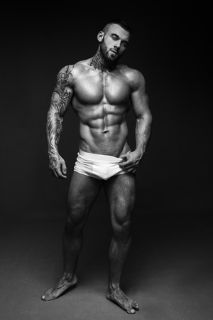 Bodybuilder image with muscle man torso. Banner image of sexy  with muscular body. Portrait of sexy male model. Hot macho in abs poses on black . 16 in 9 crop for design.の写真素材