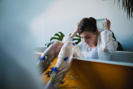 Fashion portrait of girl in plastic trend clothes. Eco styling. Model lying in bath.の写真素材