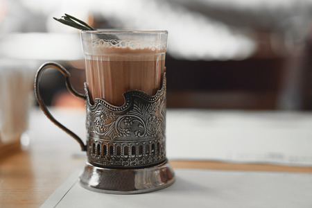 A mug of hot cocoa with a rosemary branch in a vintage metal cup holder. Retro style food photo concept. Blurred background and copy space for text, design, lettering.の写真素材