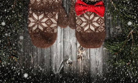Brown mittens and spruce branches with snow on black wooden background. Holiday postcard design. Christmas and New Year concept with copy space.の写真素材
