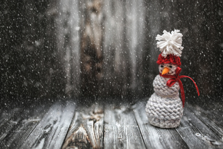 New Year winter snowman decoration with snow on black wooden background. Holiday New Year postcard frame design with copy space.の写真素材