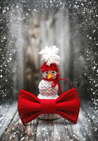 New Year winter snowman decoration with snow on black wooden background. Holiday Chrismas postcard frame design with copy space.の写真素材