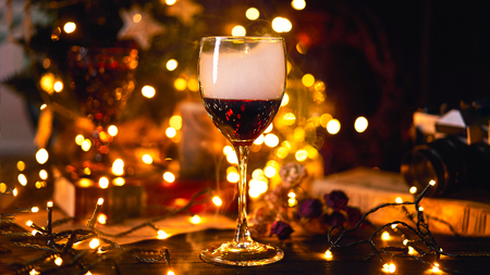 Banner size 16 in 9. Festive atmosphere with a glass of red wine. Smoke creeping in glass and light bokeh background. Christmas, New Years or Saint Valentine holiday.Golden color and soft focus.の写真素材