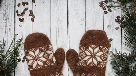 Brown mittens and spruce branches with snow on white wooden background. Holiday banner design 16 in 9 . Winter concept.の写真素材
