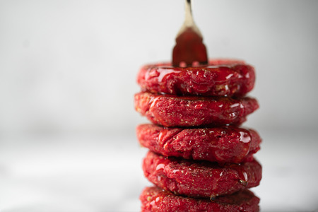 Close up of heesecakes with honey colored in red.Russian traditional breakfast.Food consept.Plate with puncakes on white marble background.Copyspace for text and design elements. Small depth of field.の写真素材