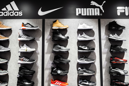 Nurmberg, GERMANY - February 27, 2019: The NIKE, ADIDAS, PUMA and FILA black sneakers on the shell in the shop. Fashionable foot wear shoes.のeditorial素材