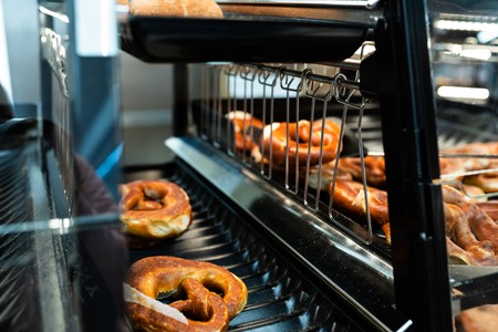 Germany national bakery - brezel. Fresh pretzel on bread shelf in store. Take a fresh bavarian Brezel with a spatula. Breakfast food concept.の写真素材