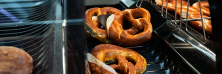 Germany national bakery - brezel. Close up Fresh pretzel on bread shelf in store. Take a fresh bavarian Brezel with a spatula. Breakfast food concept.の写真素材