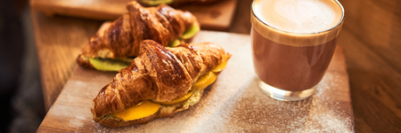 Web Banner 3 in 1 crop for design. Fresh croissant and original authors coffee with fruits on wooden table. Healthy breakfast food concept. Traditional french lunch in cafe with gold sunlight flare.の写真素材