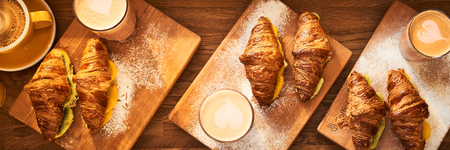 Web Banner 3 in 1 crop for design. Fresh croissant and original authors coffee with fruits on wooden table. Healthy breakfast food concept. Traditional french lunch in cafe with gold sunlight flare.の写真素材