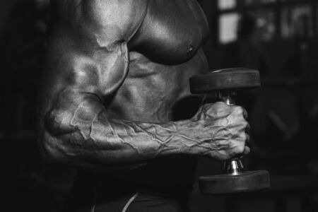 Chest press. Handsome muscular sexy man in gym doing exercises. Tanned athlete. Chest workoutsの写真素材