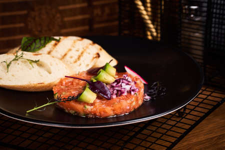 Tartare from salmon with bread on table in restaurant.の写真素材