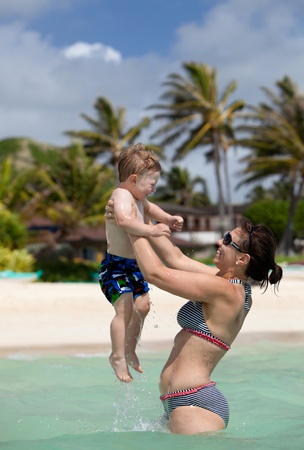 Young fit happy mother playing with her little son in the ocean の写真素材