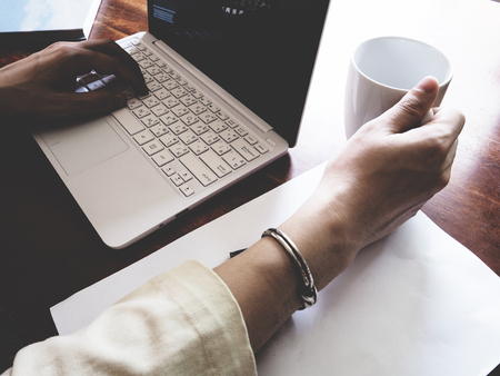 There are book, laptop, coffee cup, paper, and pencil on the office wooden  desk