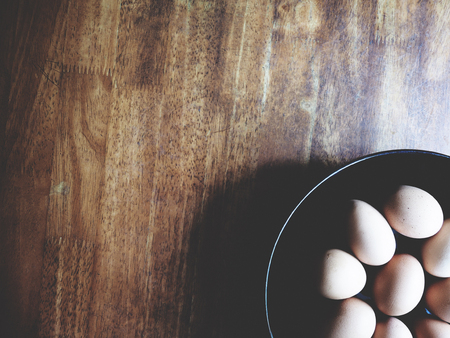 This is chicken egg in the black plate above wooden desk,  soft toneの写真素材