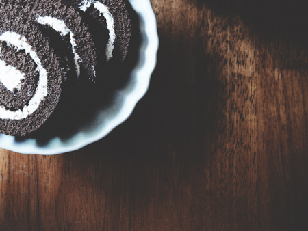 This is chocolate roll in white plate above wooden,  soft toneの写真素材