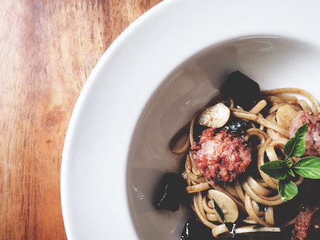 This is fried linguine with garlic, chili and fermented pork on white plate above wooden table,  soft toneの写真素材