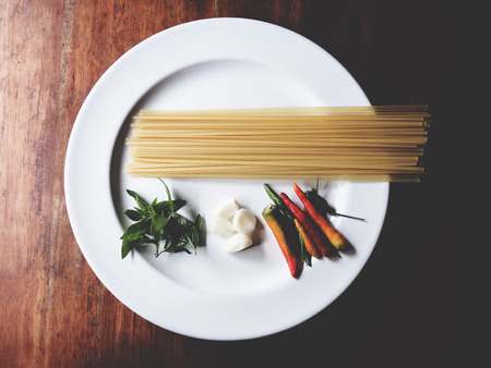 This is preparation for pasta dish, consist of dried linguine, garlic, chili and sweet basil on the...