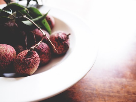 This is fresh lychee in white plate above wooden table,  soft toneの写真素材