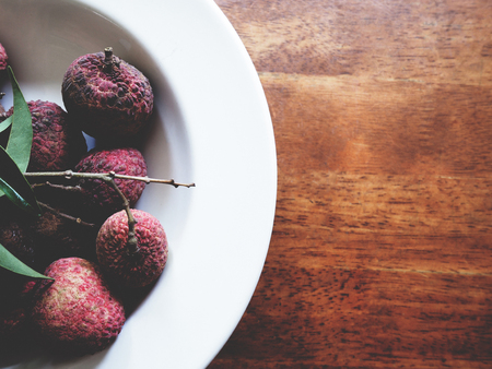 This is fresh lychee in white plate above wooden table,  soft toneの写真素材