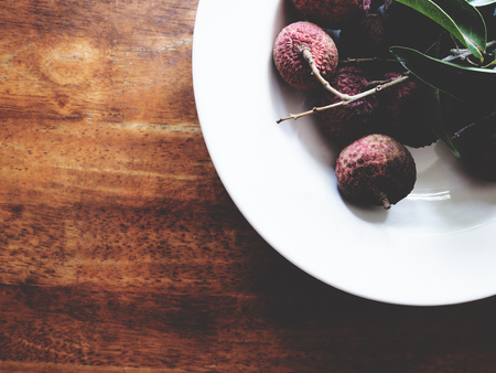 This is fresh lychee in white plate above wooden table,  soft toneの写真素材