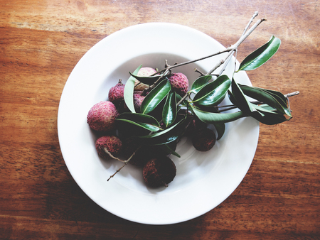 This is fresh lychee in white plate above wooden table,  soft toneの写真素材