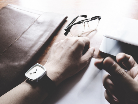 The picture of hands working action on wooden table, consist of laptop, paper, pencil, watch, glasses, soft tone colorの写真素材