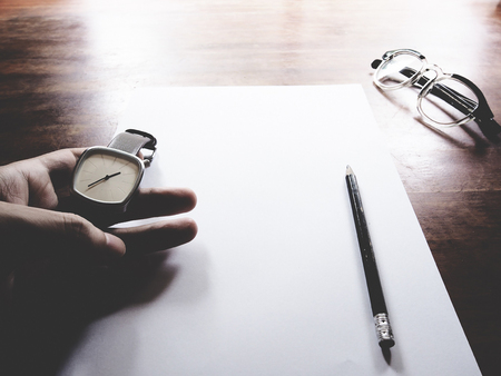This is office equipment in minimal style, The picture of pen, glasses, paper, hand and watch on wooden table. soft tone color,  minimal styleの写真素材