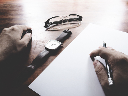 This is office equipment in minimal style, The picture of pen, glasses, paper, hand and watch on wooden table. soft tone color,  minimal styleの写真素材