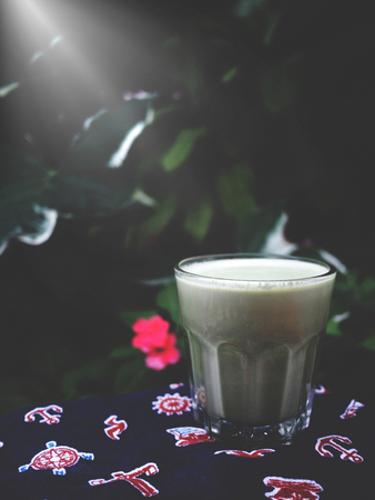 The picture of a cup of matcha latte on green tree background, while sunlight at  the morningの写真素材