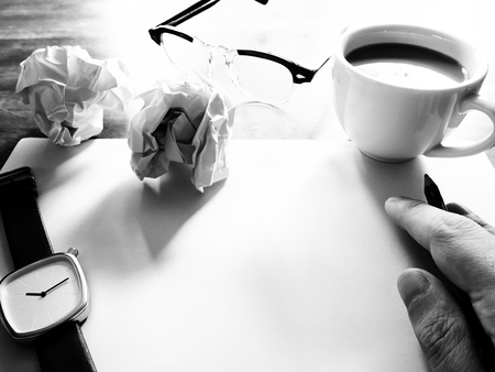 Businesses have both been successful and fail. The picture of fail work, glasses, paper, pencil, watch, a cup of coffee  and men hand gesture above wooden table.  black and white colorの写真素材
