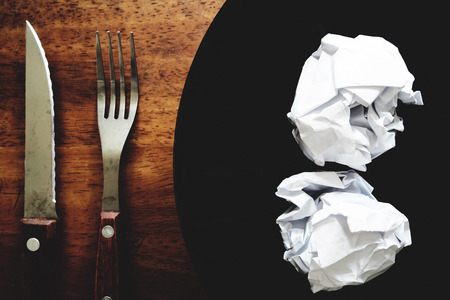 No work No money and No food. The picture of failed work condition consist of disastrously paper on white dish, pencil, fork, spoon, hand and knife above wooden table. selective focus. soft tone styleの写真素材