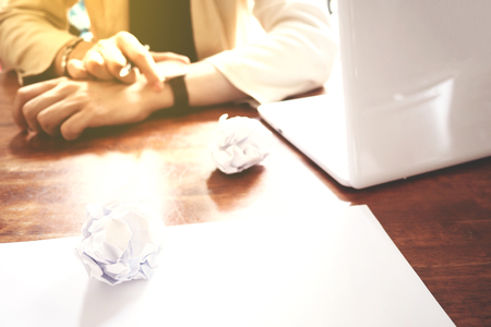 The picture of Asian Businessmen are saddened by the failure of his work on wooden table at office, consist of white laptop, paper, and hands. selective focusの写真素材