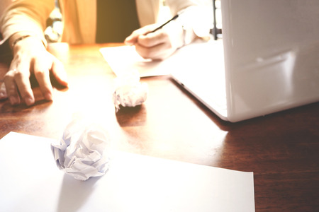 The picture of Asian Businessmen are saddened by the failure of his work on wooden table at office, consist of white laptop, paper, and hands. selective focusの写真素材