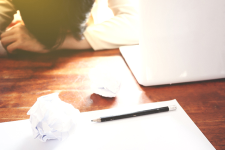 The picture of Asian Businessmen are saddened by the failure of his work on wooden table at office, consist of white laptop, paper, and hands. selective focusの写真素材