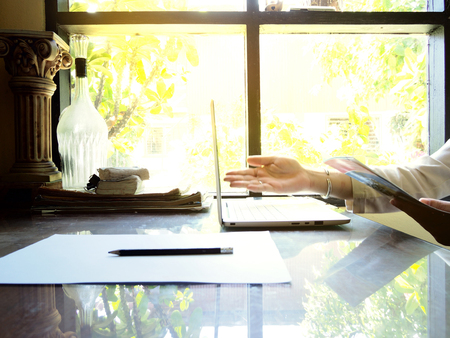 Businesses happen everywhere, just have inspiration. The picture of white laptop with Male hand on wooden table near the window at home office. selective focusの写真素材
