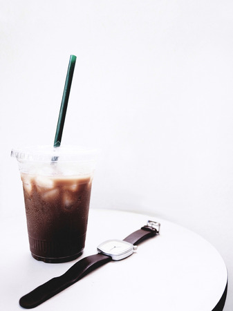 The picture of iced mocha and watch on white table on white background. minimal style. selective focusの写真素材