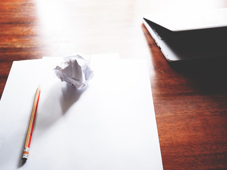 The picture of failed work action on wooden table consist of white laptop, paper and pencil. soft tone colorの写真素材