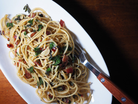 Top view picture of spaghetti fried dried chili and bacon on white dish above wooden table.の写真素材
