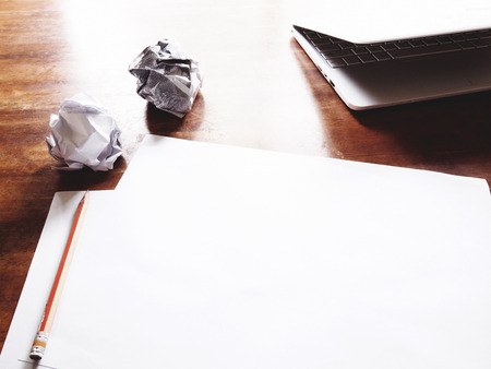 The picture of failed work action on wooden table consist of white laptop, paper and pencil. soft tone colorの写真素材