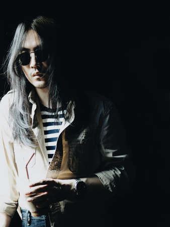 Portrait of white Asian men long hair hold coffee cup, dress casual style on black background. Light and shadow portrait styleの写真素材