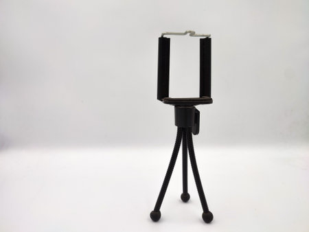 Photo of a small black tripod on a white background in a studio.の写真素材