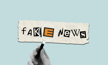 Hand holding magnifying glass above fake news letter collage on torn paper. Identifying false info, attention to detail concept.の写真素材