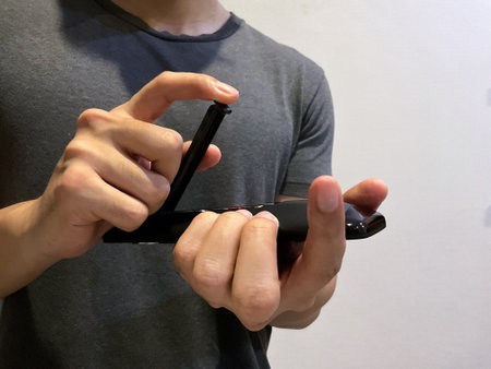 Person changing tv remote control battery manually using hand close up view, no face shown on cameraの写真素材