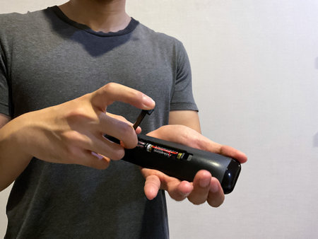 Person changing tv remote control battery manually using hand close up view, no face shown on cameraの写真素材