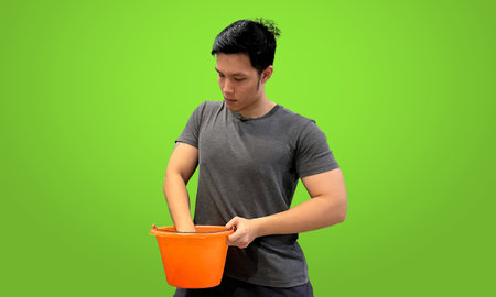Person reaching into orange bucket looking for something. Casual wear, isolated on green screen background.の写真素材
